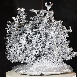 Silver metal art sculpture created from aluminum casting of a complex fire ant colony nest.