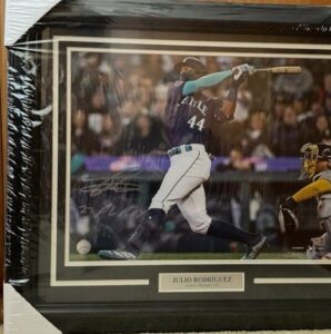 Framed and autographed 24x28 action photograph of Seattle Mariners baseball player Julio Rodriguez swinging a bat.